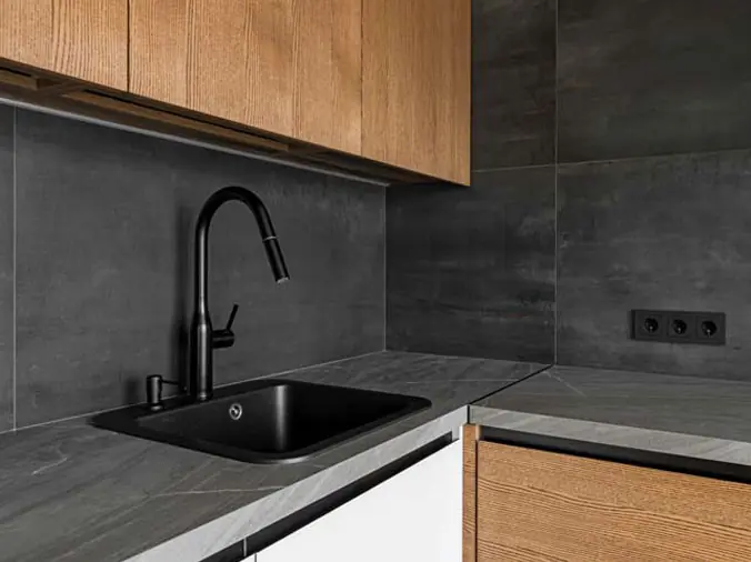 kitchen sink with black faucet and dark grey countertop and backsplash
